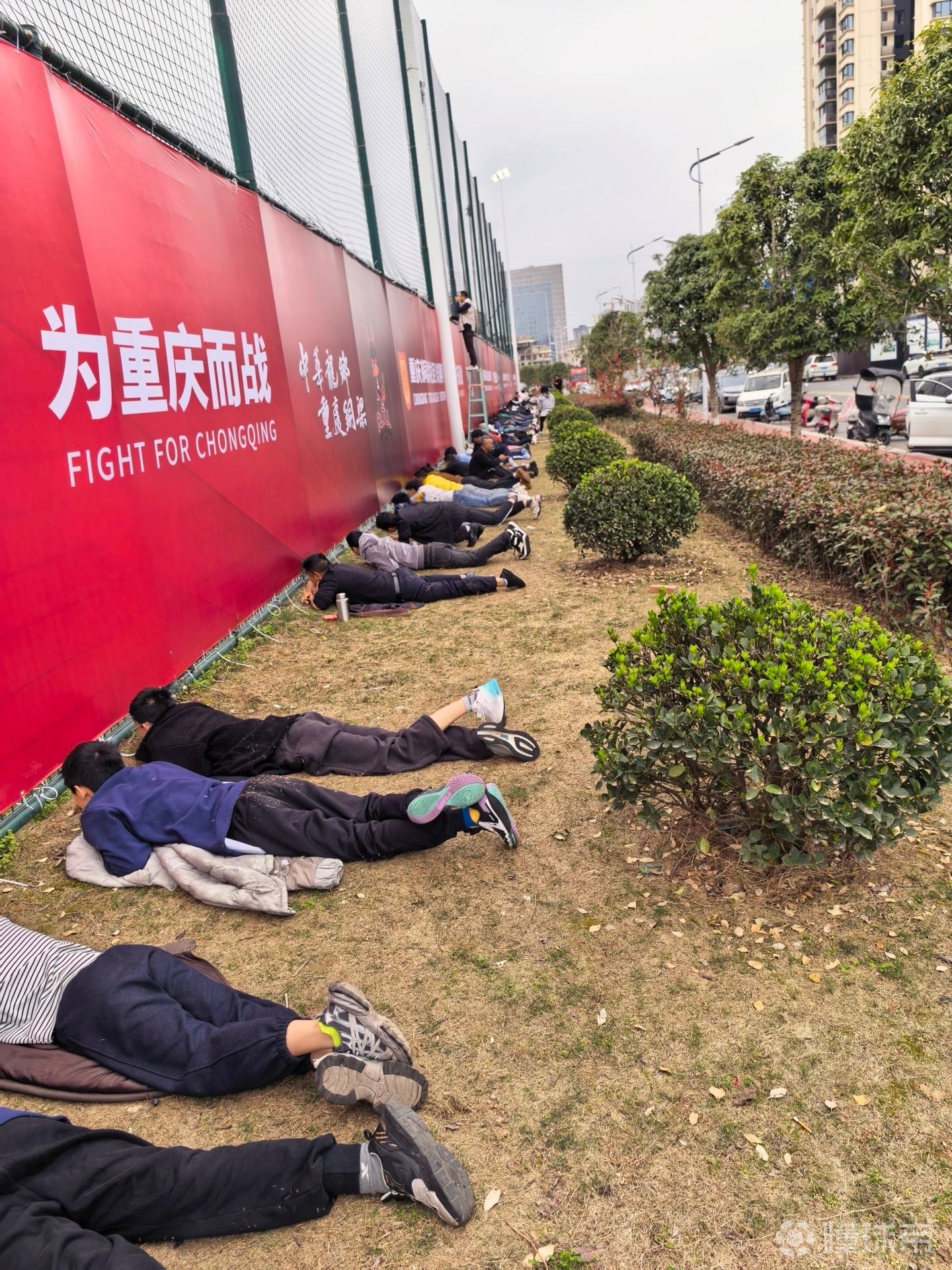 接地气，重庆球迷趴在草地上透过围栏缝隙观看铜梁龙热身赛